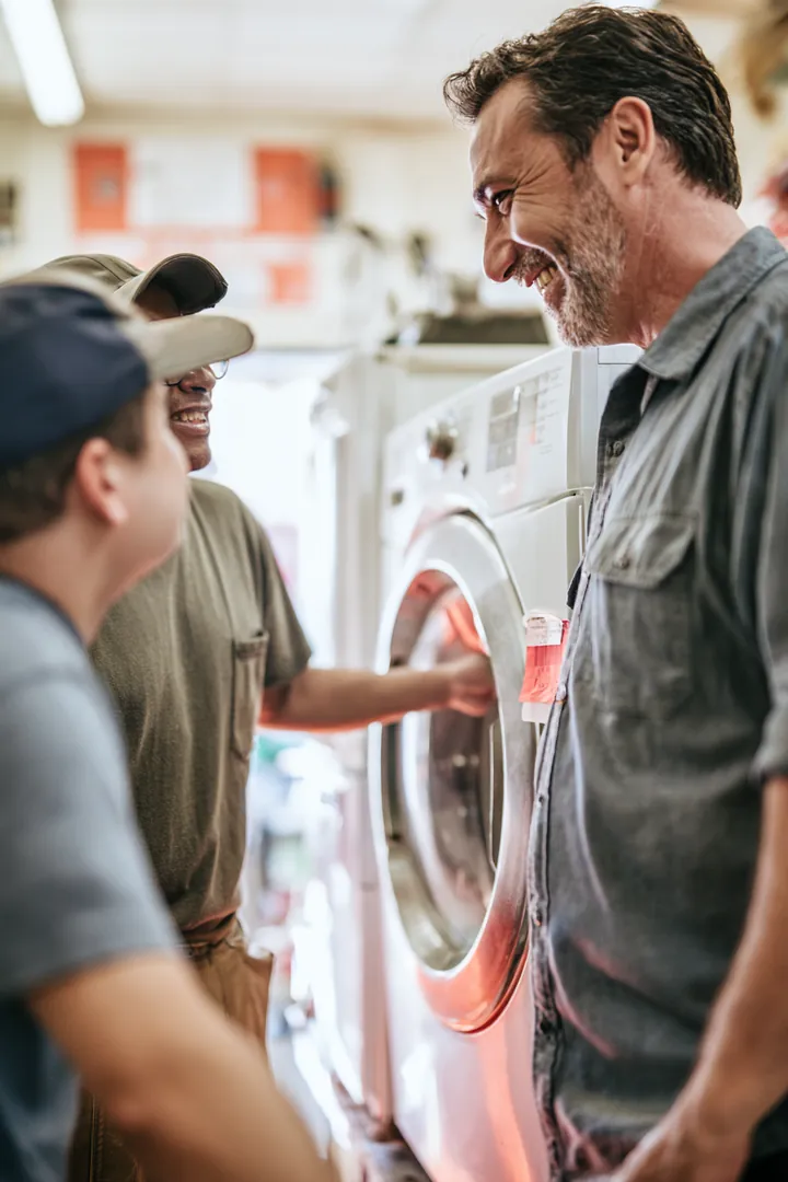Customers discussing a used washer and dryer set with an attendant at an appliance store