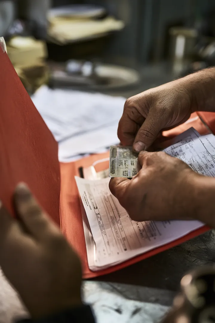 Hands organizing an ID card and pay stubs into a document folder before a personal loan request