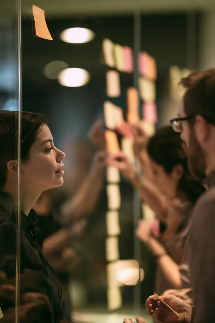 Team sorting borrowers' personal loan questions written on sticky notes into columns on a glass wall