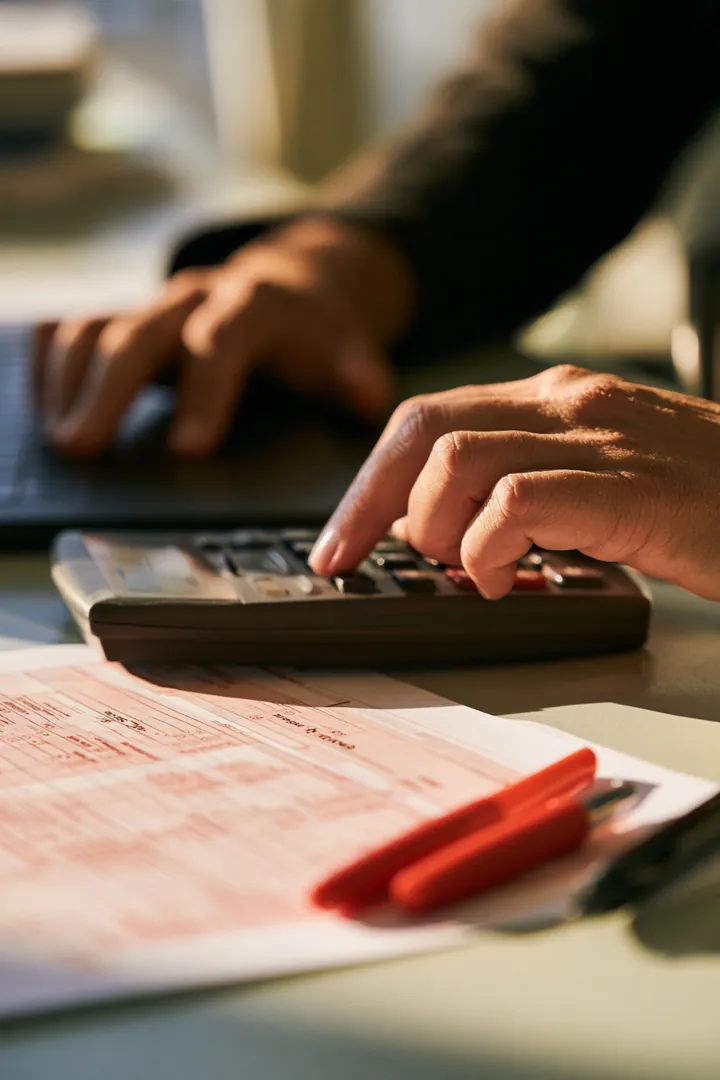 Hands working a calculator beside a printed personal loan rate comparison worksheet