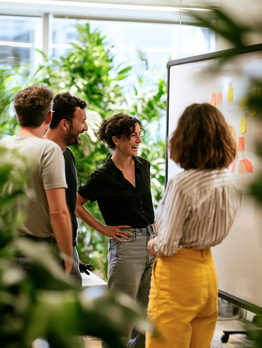 The Benemoney team in a casual stand-up meeting around a whiteboard
