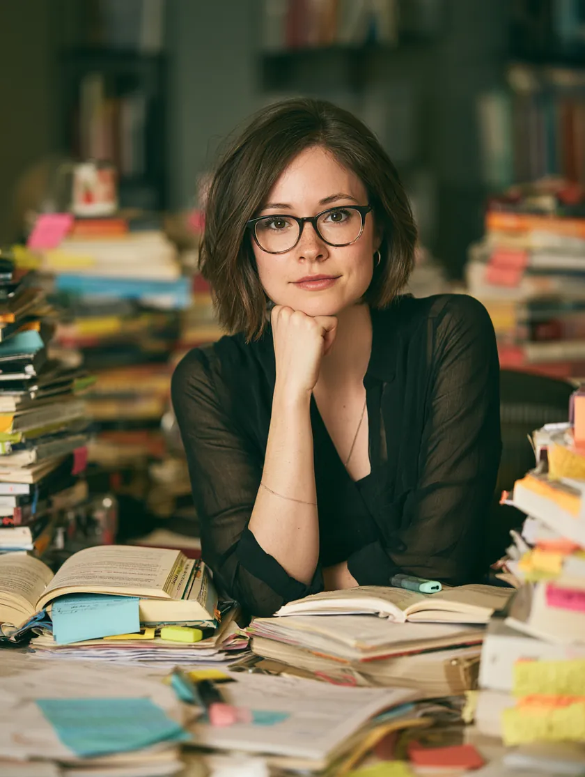 Professional surrounded by open reference books with colorful sticky notes marking loan terms